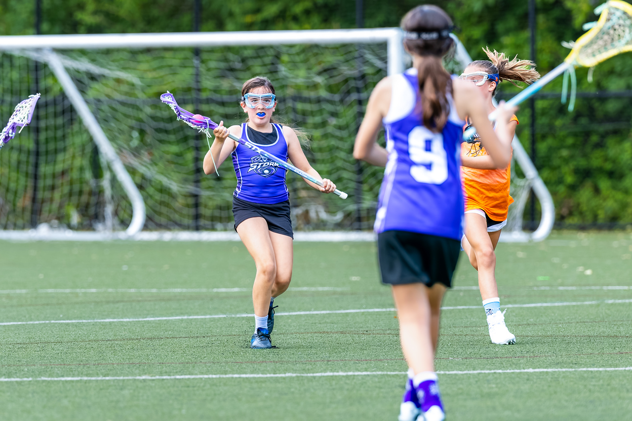 A Sixers player cradles the ball as teammates close in on the turf